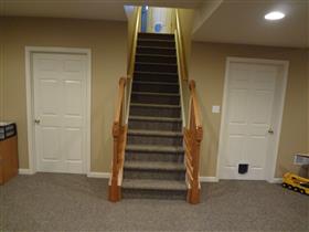 *After* - Finished steps with carpet, oak railing, and added doors to close off laundry area & utility/storage area.: 